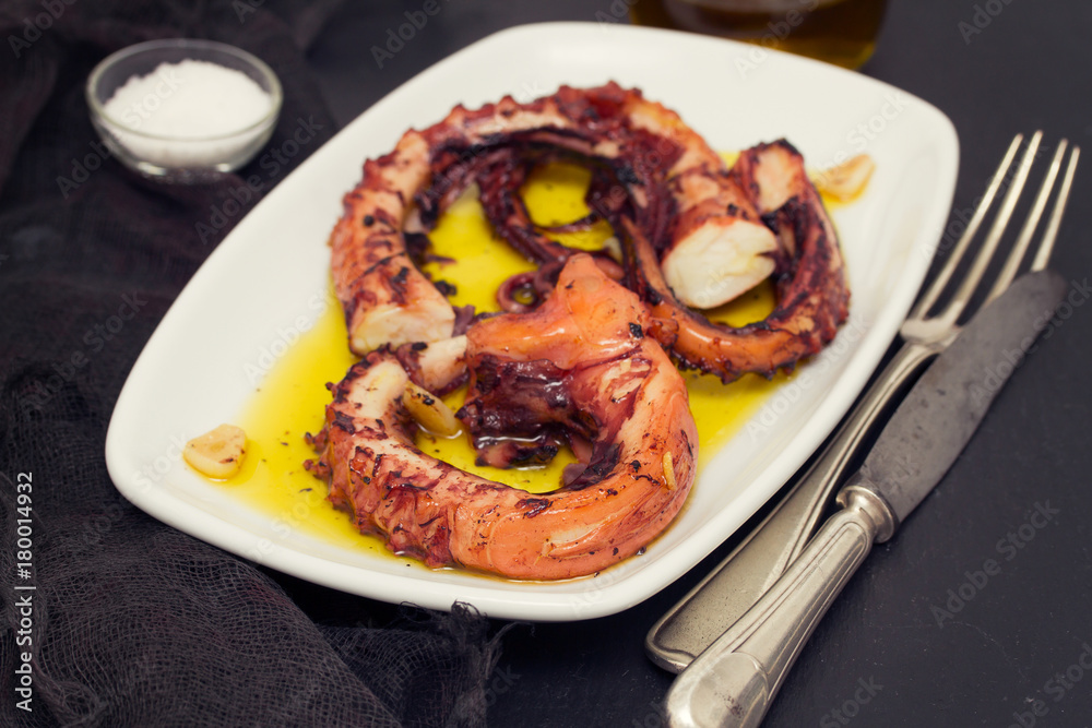 grilled octopus with garlic on white dish on wooden background grilled octopus with garlic on white dish on wooden background