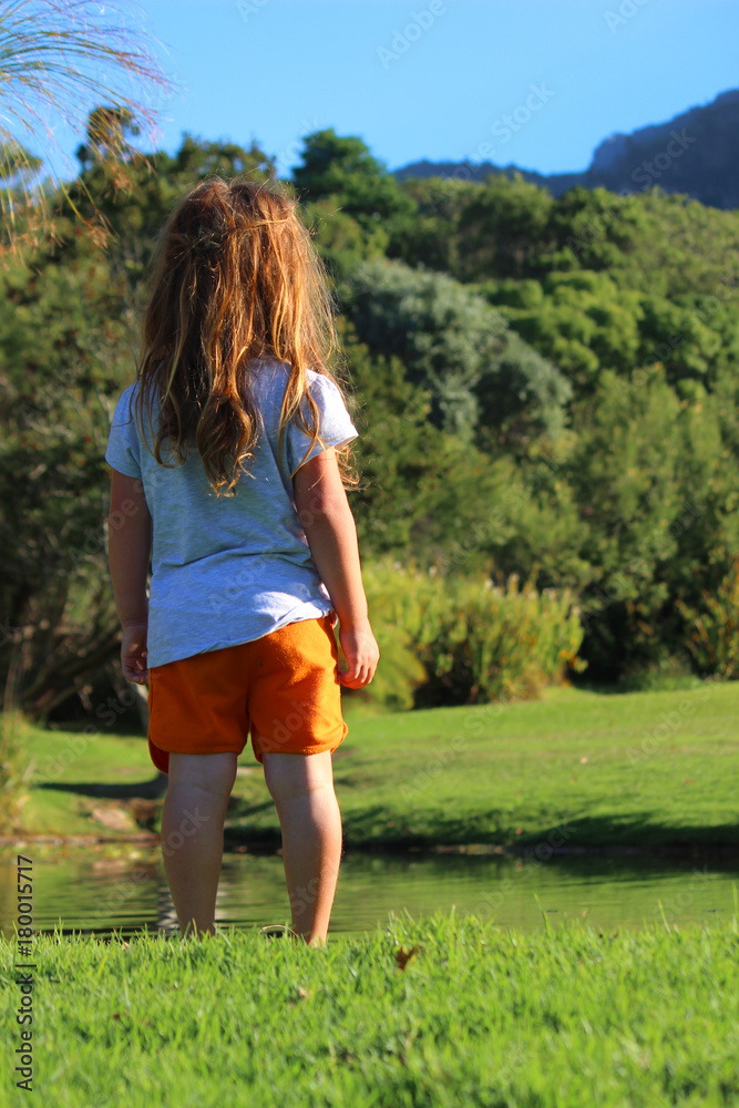 red hair girl with bright orange pants walks in bright green  garden