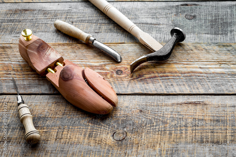 Tools for repair shoes. Wooden last, hammer, awl, knife, thread on wooden background copyspace