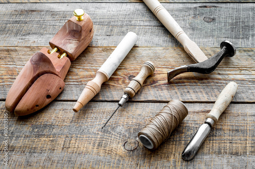 Tools for repair shoes. Wooden last, hammer, awl, knife, thread on wooden background