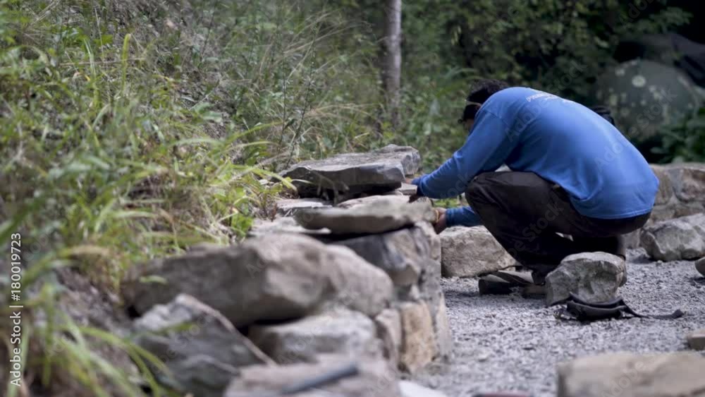 Using a sponge, a hardscaper wipes the mortar between the rocks in a stone wall. Using a sponge, a hardscaper wipes the mortar between the rocks in a stone wall.