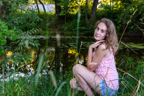 smiling girl sitting on the river bank