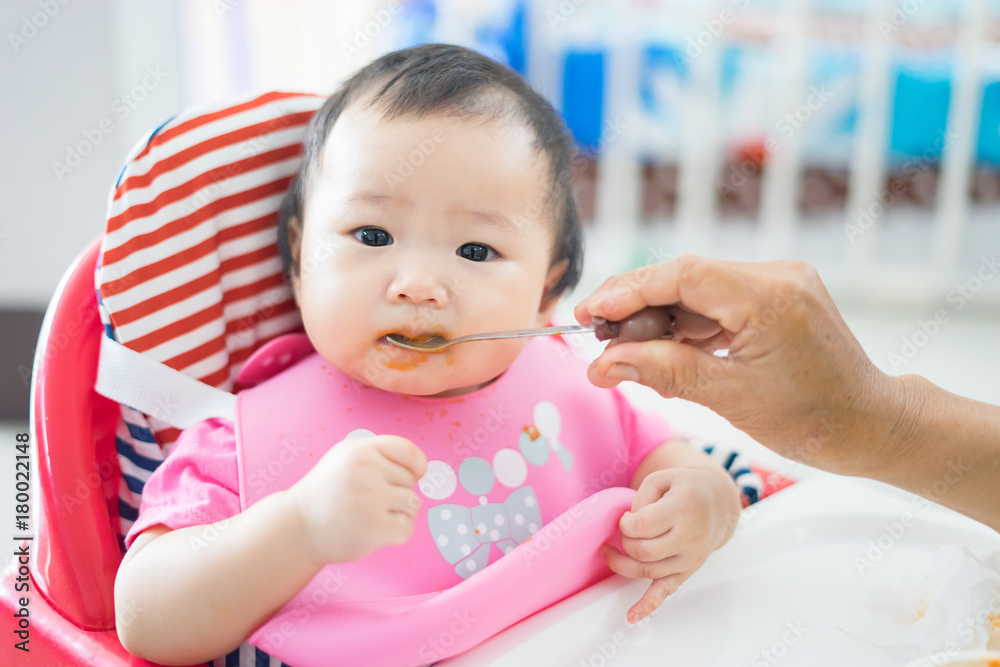 mother feeding food for young asian baby ,Mum spoon-feeds the child