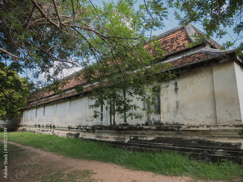 Dirt road through forest and yard in ancient Ayutthaya temple on sunny day