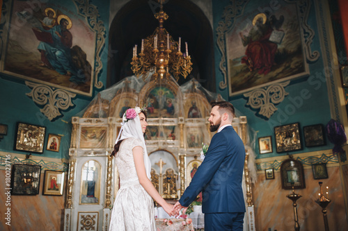 Newlyweds standing in front of the altar during the wedding ceremony. © shchus