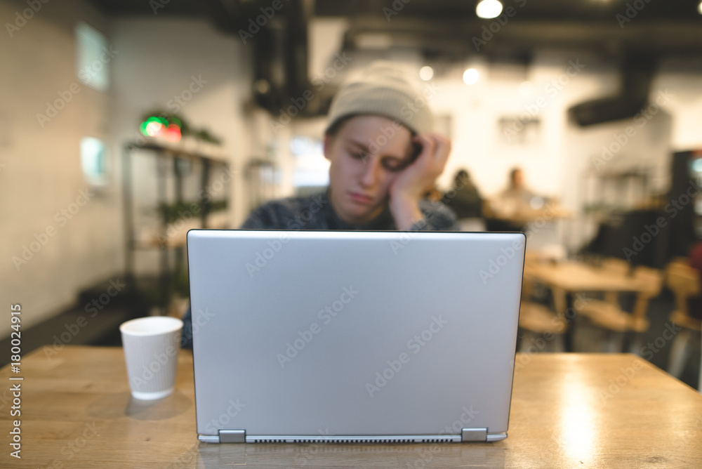 A sleepy freelancer sits in a cozy cafe and works for a laptop. Hipsters in a cafe with a laptop. Focus on the laptop. A sleepy freelancer sits in a cozy cafe and works for a laptop. Hipsters in a cafe with a laptop. Focus on the laptop.