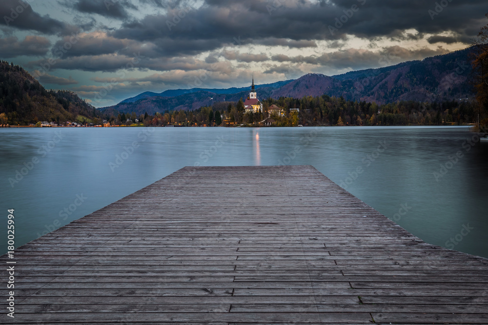 Bled, Slovenia - Sunset at the beautiful Lake Bled with Pilgrimage Church of the Assumption of Maria and pier and amazing clouds at autumn