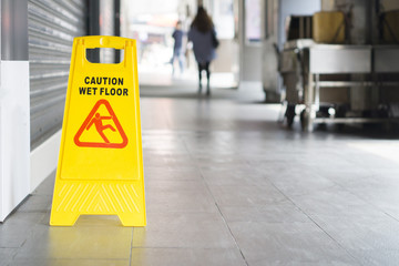 yellow sign inside building hallway showing warning of caution wet floor,selective focus,vintage color.