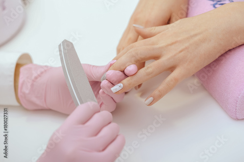 manicure worker smoothing customers nails with nail file