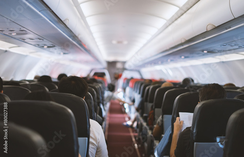Konstfotografi passenger seat, Interior of airplane with passengers sitting on seats and stewardess walking the aisle in background