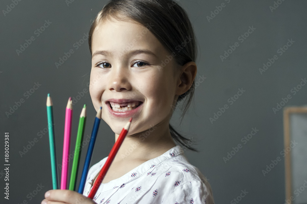Happy child holding colored pencils and smiling broadly. Happy child holding colored pencils and smiling broadly.