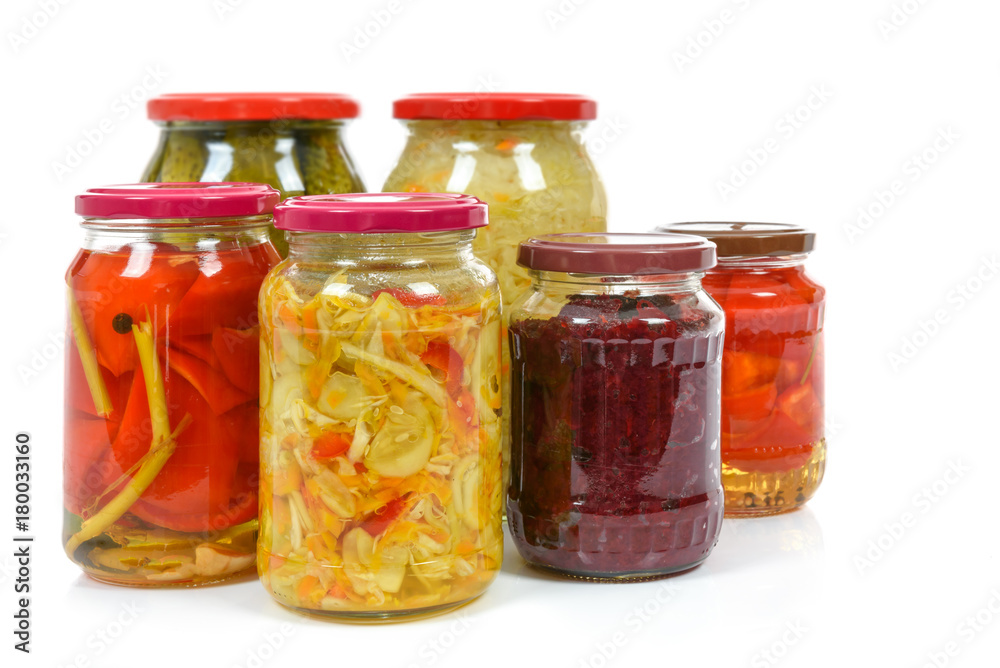 Jars with variety of homemade pickled vegetables isolated on a white background.