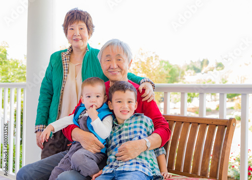 Senior Adult Chinese Couple Sitting With Their Mixed Race Grandchildren
