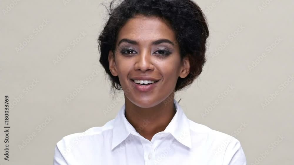Close up view of smiling african woman in shirt sends air kiss at the camera over gray background Close up view of smiling african woman in shirt sends air kiss at the camera over gray background