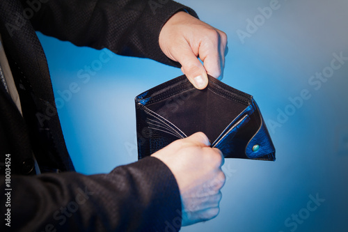 Broke businessman opening empty wallet showing he has no money