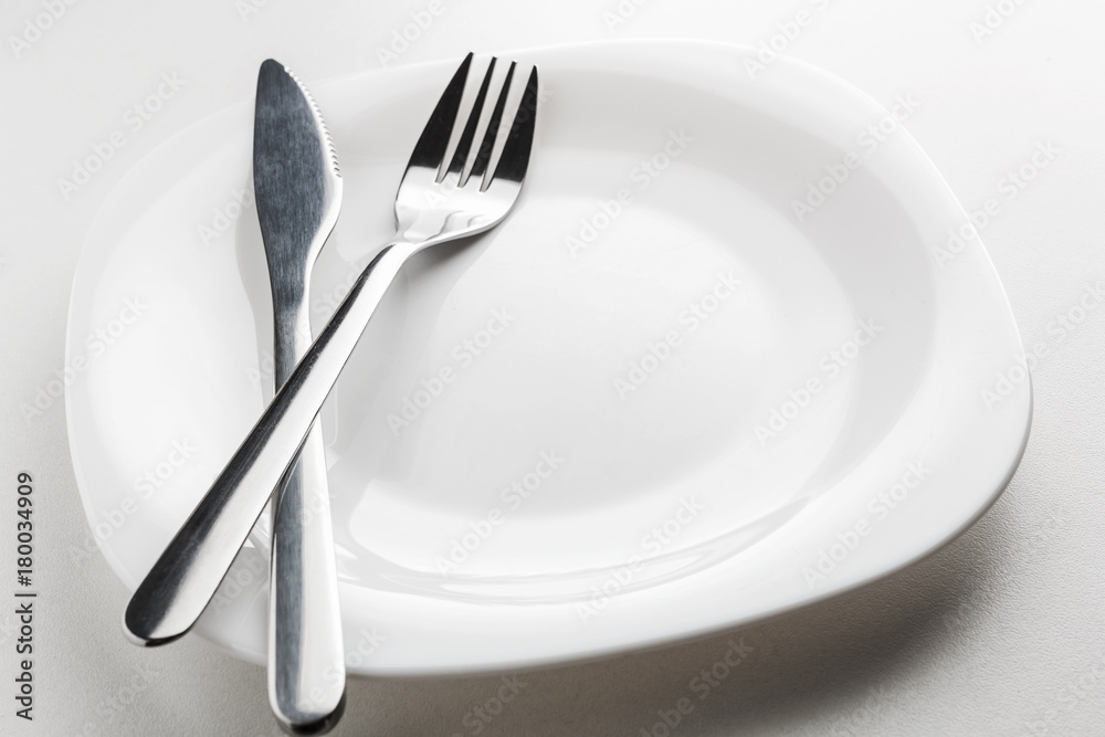 empty white plate, fork and knife on a white background. empty white plate, fork and knife on a white background.