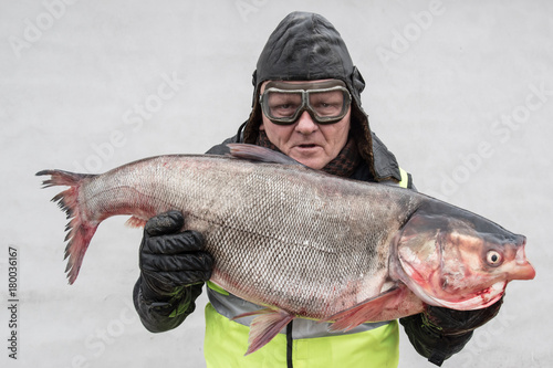 An elderly fisherman shows a large fish.
