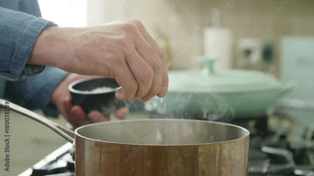 Man Sprinkling Salt From Bowl In Saucepan Man Sprinkling Salt From Bowl In Saucepan