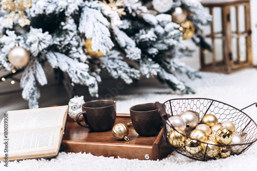Close-up photo of a tray with two cups of hot drinks and a book. Christmas and New Year concept