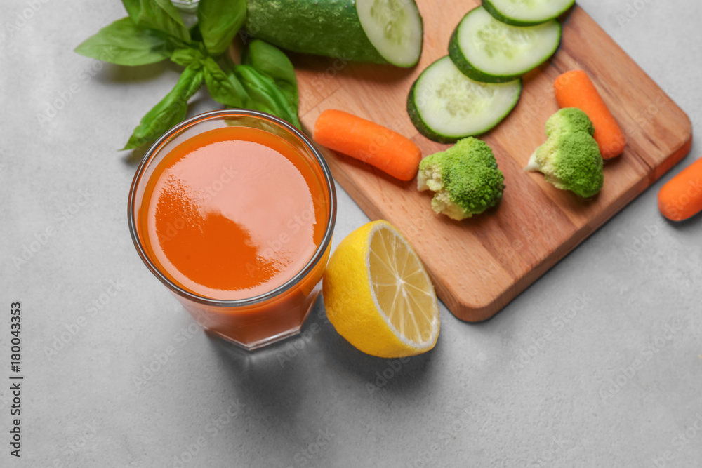 Glass of fresh juice with ingredients on table