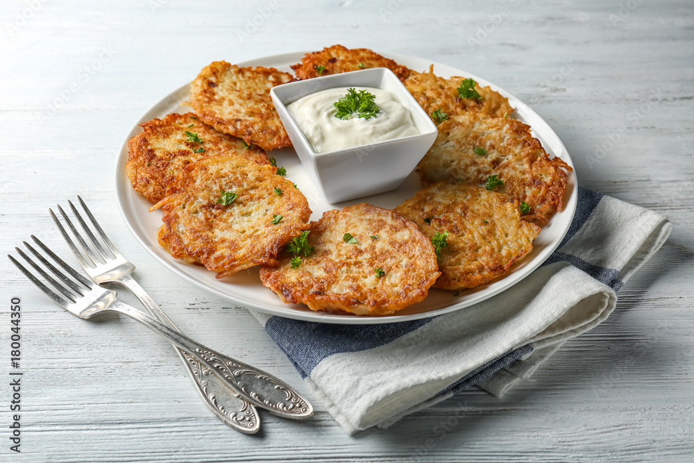 Plate with Hanukkah potato pancakes and sauce on table Plate with Hanukkah potato pancakes and sauce on table