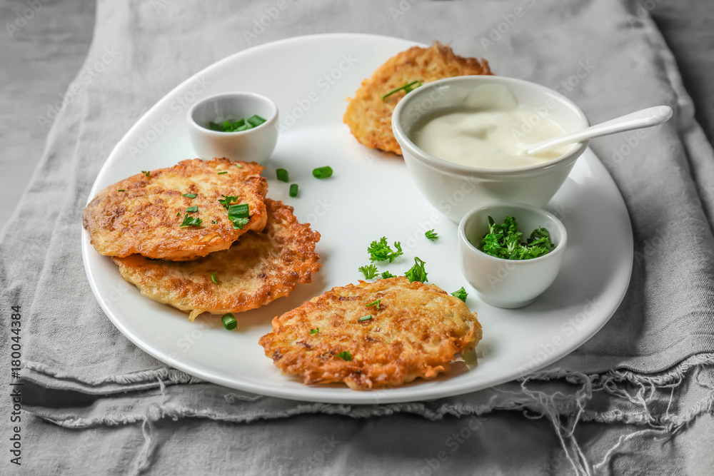 Plate with Hanukkah potato pancakes and sauce on table Plate with Hanukkah potato pancakes and sauce on table