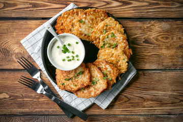 Plate with Hanukkah potato pancakes and sauce on table
