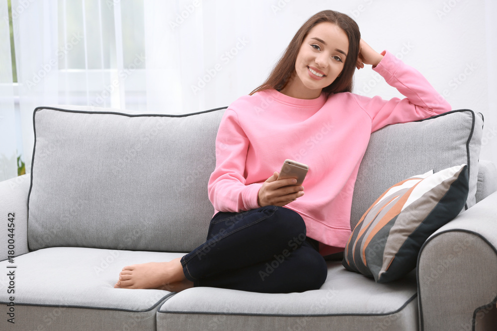 Young woman with mobile phone on sofa at home Young woman with mobile phone on sofa at home