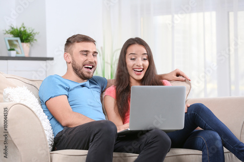 Young couple with laptop on sofa at home