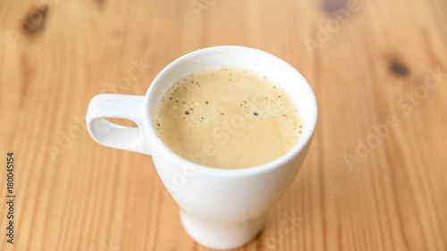 Kaffee Crema ain einer weißen Tasse auf einem Holztisch