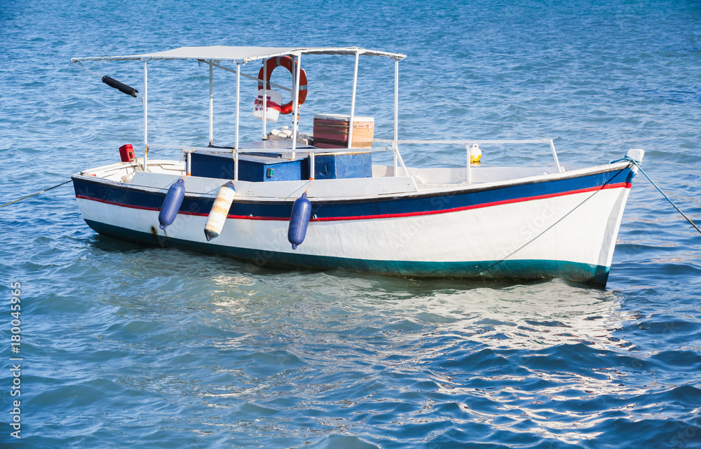 Fototapeta premium White wooden fishing boat anchored in port