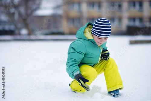 Portrait of little boy playing with snow in winter