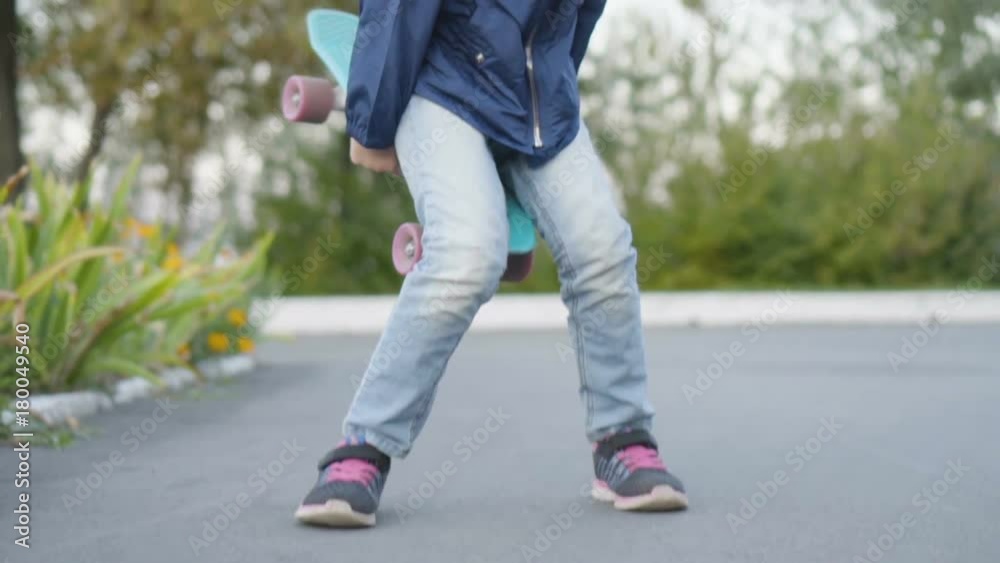 little girl standing up with mini cruiser board after riding it. slow motion little girl standing up with mini cruiser board after riding it. slow motion