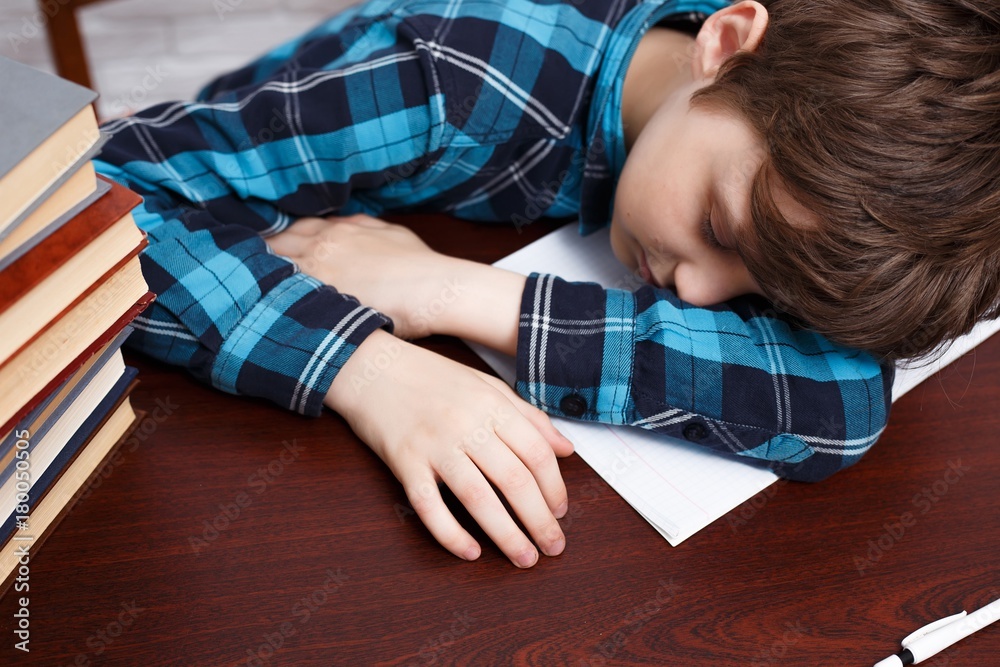 Schoolboy falling asleep while studying at copybook. School life, education, childhood, people, homework and school concept Schoolboy falling asleep while studying at copybook. School life, education, childhood, people, homework and school concept