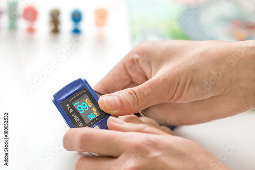 Doctor measuring kid's oxygen saturation level with finger oxymeter monitor. Healthcare , health indicator