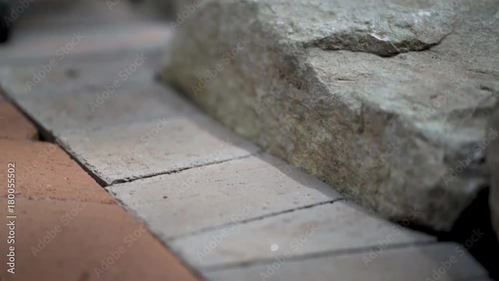 Construction zone detail showing the soldier course under construction along a rock wall as part of a brick paver project. Construction zone detail showing the soldier course under construction along a rock wall as part of a brick paver project.