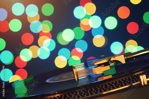 Turntable vinyl record player. Sound technology for DJ to mix & play music. Vintage vinyl record player on a background decorations for a party, bright disco lights. Needle on a vinyl record