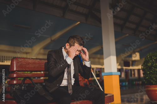 Young asian businessman feel stressed/worry/headache/disappoint during working while sit at train station, vintage photo and film style.