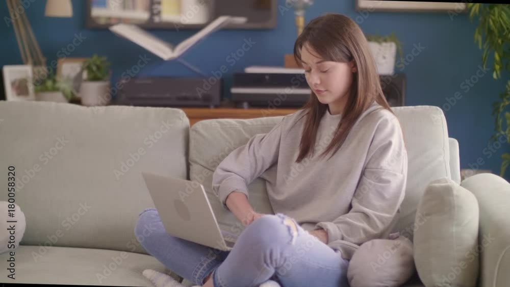 Female Blogger Using Laptop While Sitting On Sofa At Home Female Blogger Using Laptop While Sitting On Sofa At Home