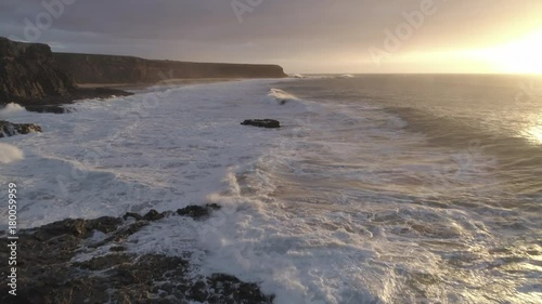 Aerial Footage Of Waves Rushing Towards Rocky Cliff During Sunset