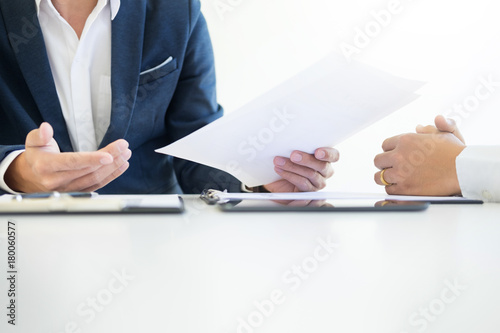 Man signing a car insurance policy, the agent is holding the document.