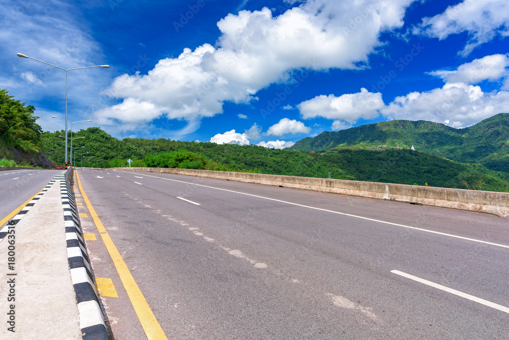 Fototapeta premium Asphalt road and mountains landscape under morning sky with clouds