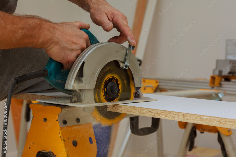 The builder cuts the board with a circular saw