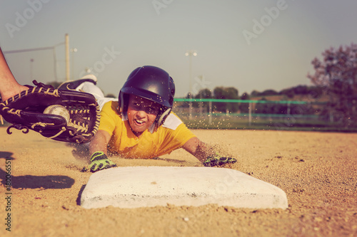 Youth Baseball playing sliding back to base.