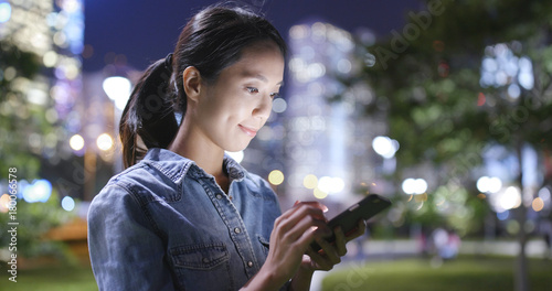 Canvas Print Young woman use of mobile phone in city of Hong Kong at night
