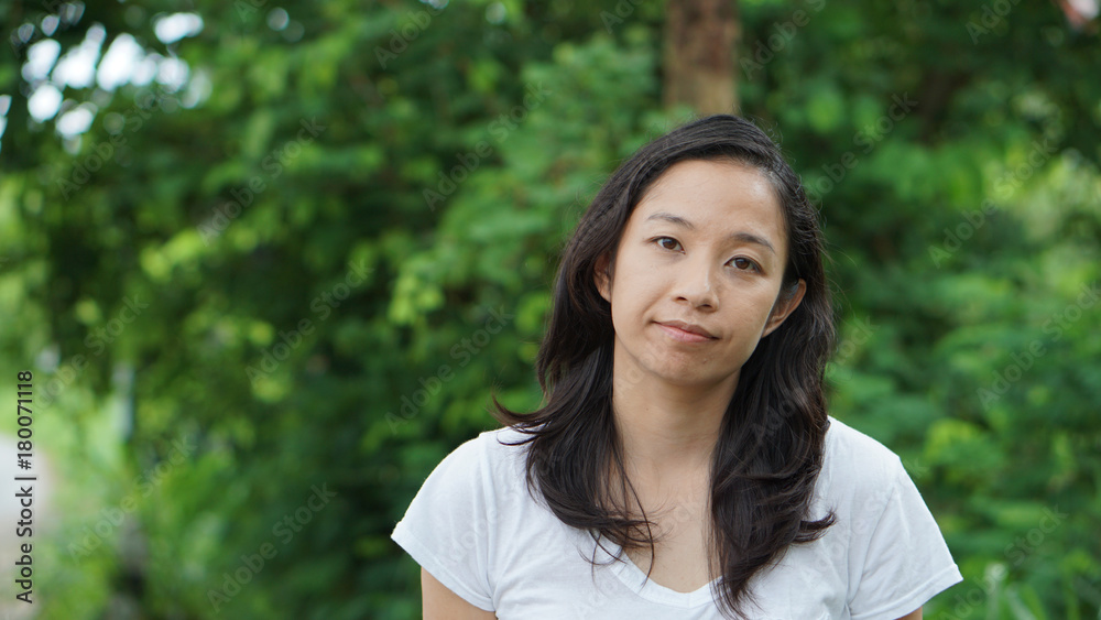 Asian woman long hair with facial epression green nature background Asian woman long hair with facial epression green nature background