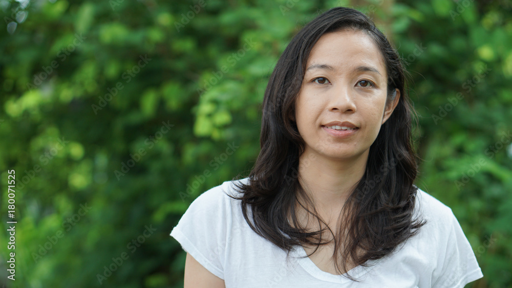 Asian woman long hair with facial epression green nature background Asian woman long hair with facial epression green nature background
