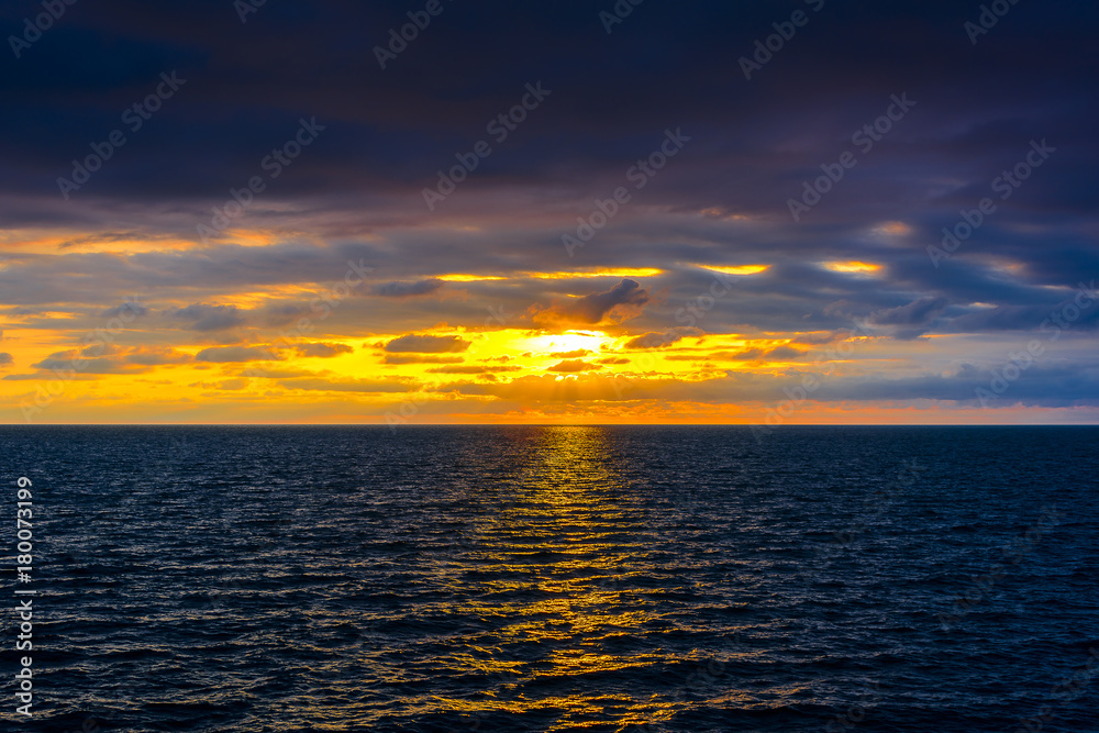 Stylized abstract landscape seascape sunset long exposure with clouds under different shades of blue, orange, yellow and red.
