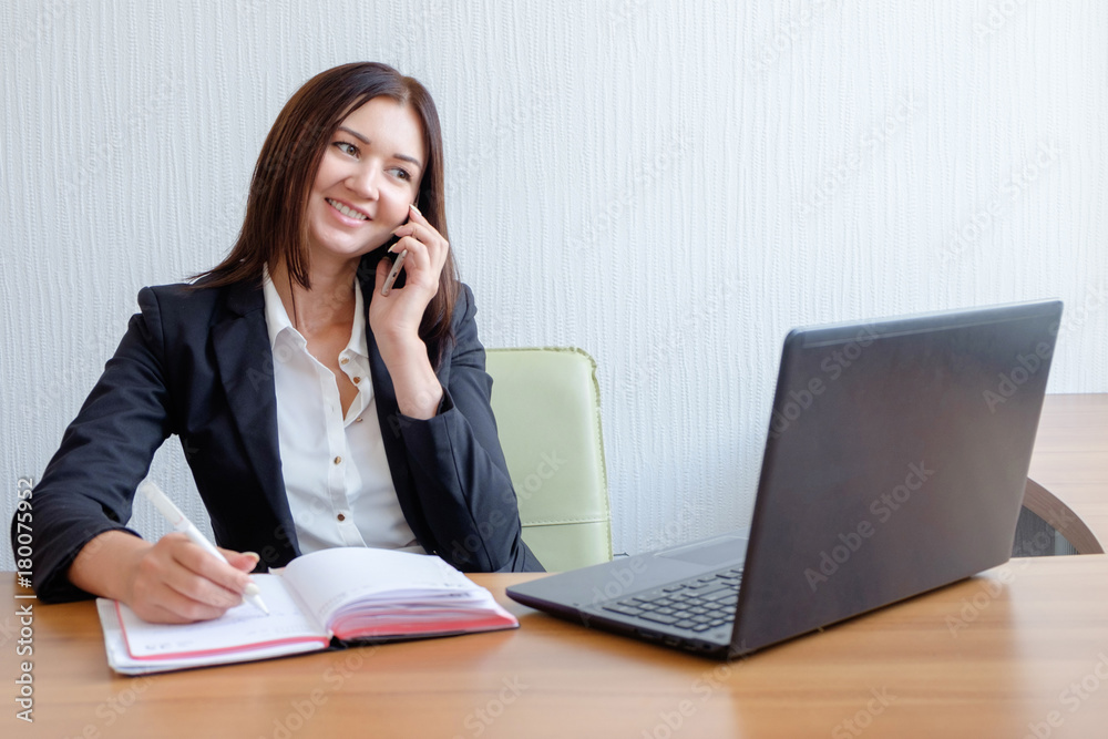 Business woman working on her laptop and talking on the phone Business woman working on her laptop and talking on the phone