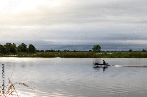 Fisherman on motor boat on lake.